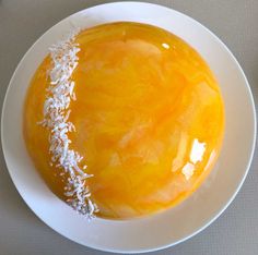 a white plate topped with an orange sauce and coconut sprinkled on top of it