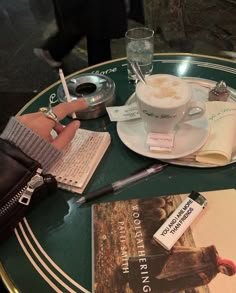 a person sitting at a table with a cup of coffee and some books on it