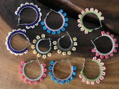 six pairs of beaded hoop earrings sitting on top of a wooden table