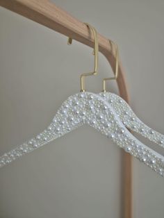 a pair of white pearls hang from a wooden coat rack on a clothes rod in a bedroom