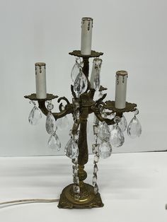 an antique brass candelabra with crystal beads and two candles on the base