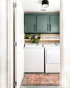 a washer and dryer in a small room with green cabinets on the wall