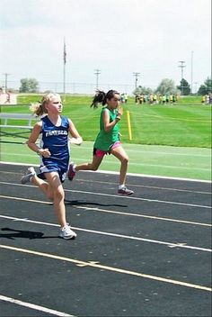 two girls running in a race on a track