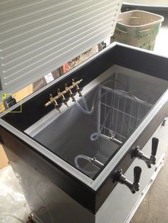 a large metal sink with two faucets on the side and three hoses attached to it