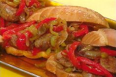 two hot dogs covered in peppers and onions on a plate with french fries next to it