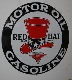 a red hat gasoline sign on the side of a white wall with black and red lettering