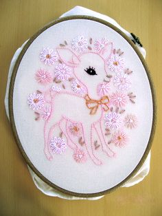 an embroidered deer with pink flowers on it's back is sitting in front of a wooden table