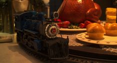 there is a toy train on the table next to oranges and other food items