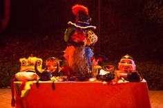 a group of clowns sitting on top of a red table cloth covered tablecloth