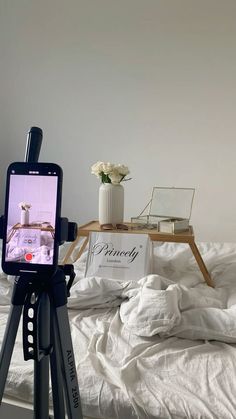 a tripod with a cell phone on top of it in front of a bed