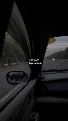 the view from inside a car driving down a road at night with fog in the distance