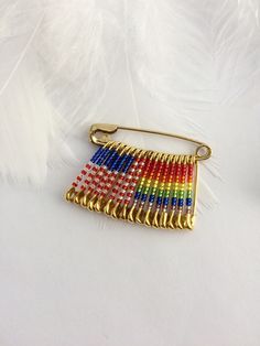 a rainbow colored pin sitting on top of a white table next to a feather quill