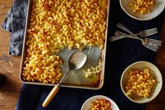 a pan filled with macaroni and cheese on top of a wooden table