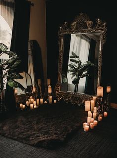 candles are lit in front of an ornate mirror with palm trees on the table and other decorations