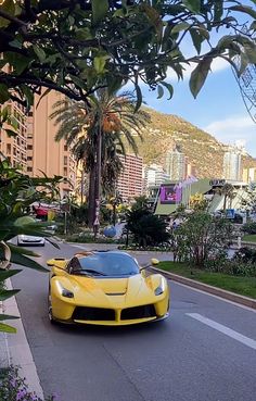 a yellow sports car is driving down the street in front of some palm trees and buildings