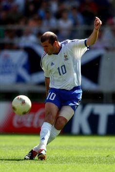 a man kicking a soccer ball on top of a field