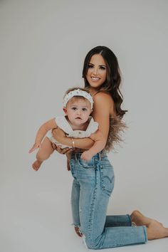 a woman holding a baby in her arms and smiling at the camera while posing for a photo