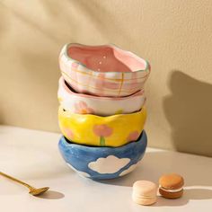 a stack of ceramic bowls sitting on top of a table next to a gold spoon