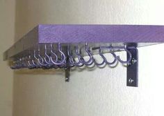 a purple shelf with several hooks on it