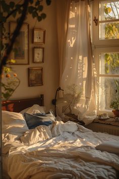 an unmade bed in front of a window with white sheets and pillows on it