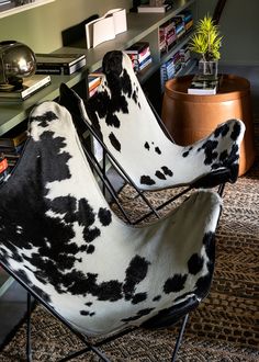 two black and white chairs sitting in front of a book shelf