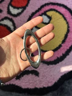 a hand holding a metal object in front of a rug with an oval design on it