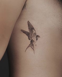 a small bird tattoo on the back of a man's left side shoulder and chest