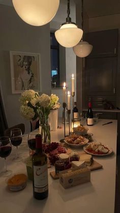 a table topped with plates and bottles of wine next to two candles on top of a counter