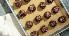 chocolate covered donuts with sprinkles on a baking sheet, ready to be eaten