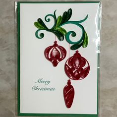 a christmas card with ornaments hanging from it