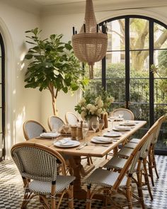 a dining room table with chairs and plates on it, in front of an arched window