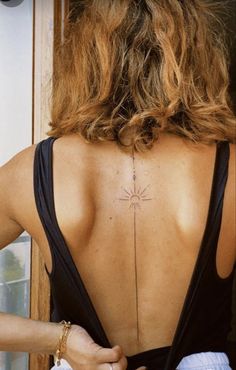 the back of a woman's neck with a cross tattoo on it