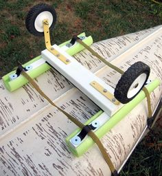 an upside down surfboard sitting in the grass with wheels attached to it's sides