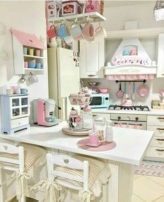 a kitchen filled with lots of white appliances and pink accessories on the counter top in front of a refrigerator freezer