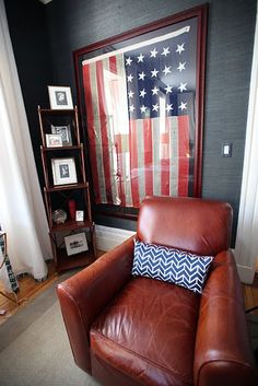 a living room with an american flag on the wall and a leather chair in front of it