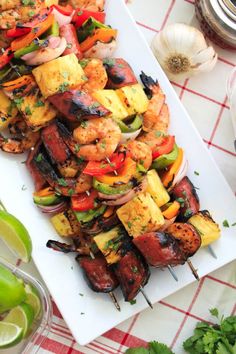 grilled chicken and vegetable kabobs on a white platter with lime wedges