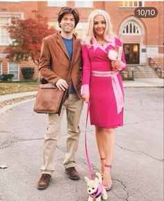 a man and woman standing next to each other with a dog on a leash in front of a brick building