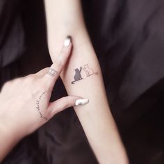 two people holding hands with tattoos on their fingers and one has a cat tattoo on the wrist