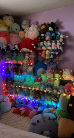 a room filled with lots of stuffed animals and lights on the wall next to a bed