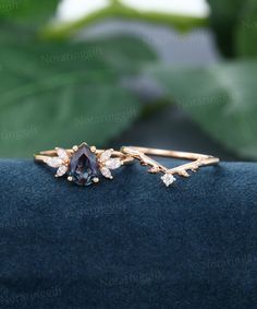 an image of two rings on top of a blue cloth with leaves in the background