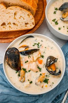 two bowls of clam chowee with bread on the side