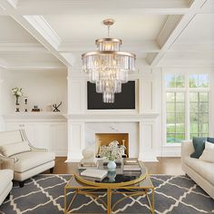 a living room filled with furniture and a chandelier hanging from the ceiling over a fire place