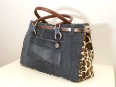 a handbag made out of denim and leather with a giraffe print lining