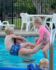 a man and two children are playing in the pool with each other while another child watches