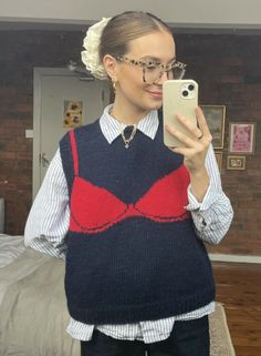 a woman taking a selfie while wearing a sweater and tie with her cell phone