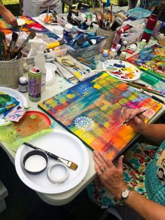 the woman is painting on her canvas at the table