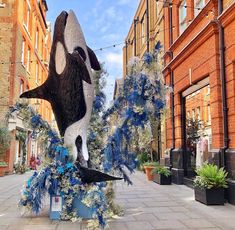 a statue of a whale is on display in the middle of a street with buildings