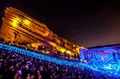 a large group of people standing in front of a mountain with lights on it at night