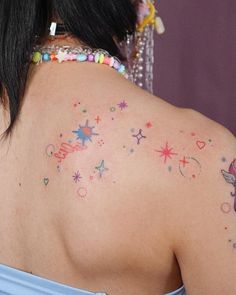 the back of a woman's shoulder with colorful tattoos on her left arm and chest