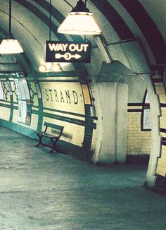 an empty subway station with benches and lights